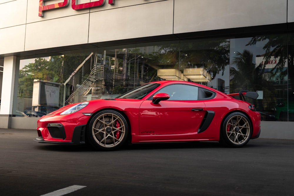 um carro esportivo vermelho estacionado em frente a um prédio