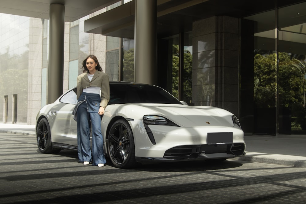 a woman standing next to a white sports car