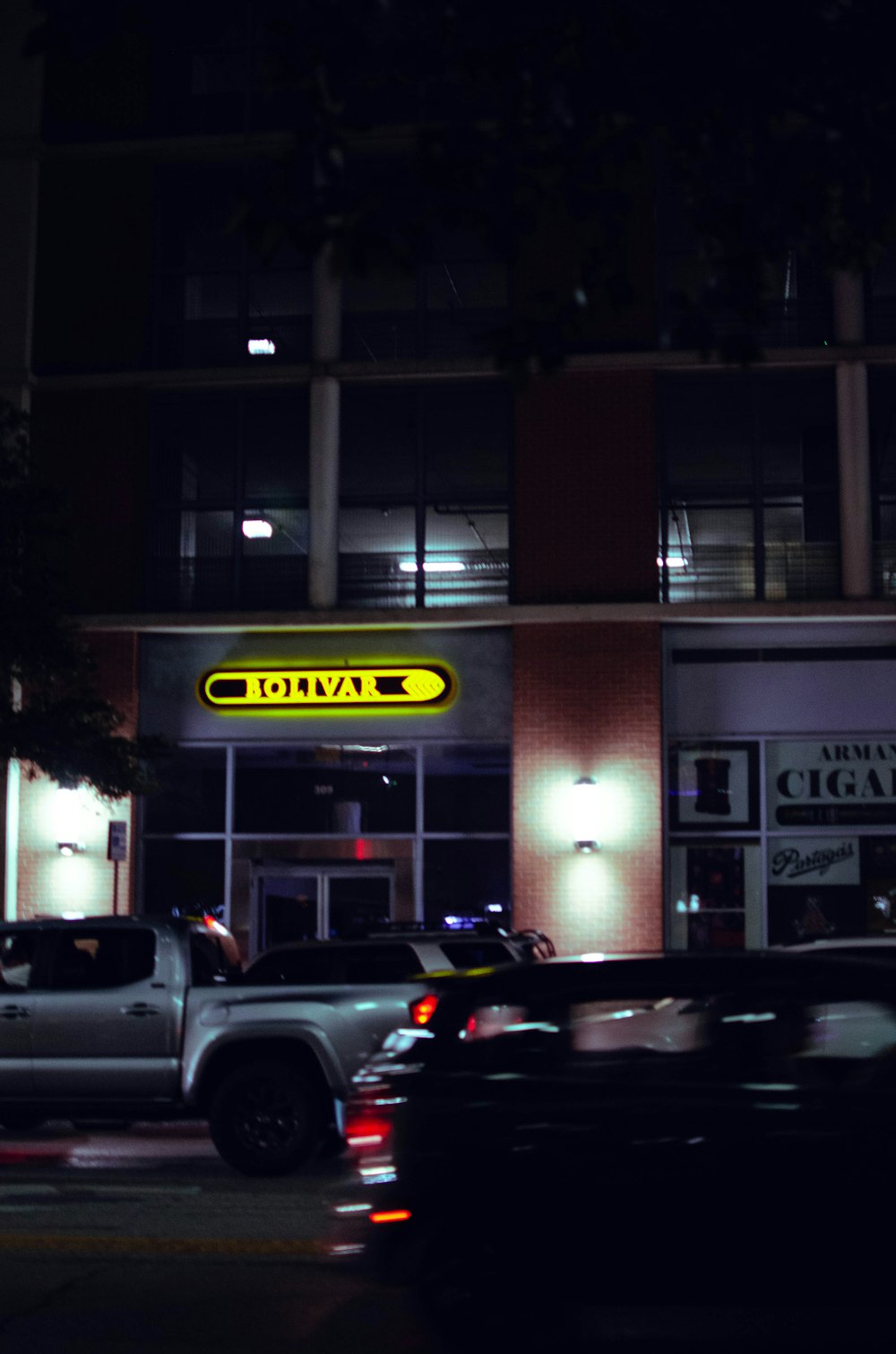 a night time view of a building with cars parked in front of it