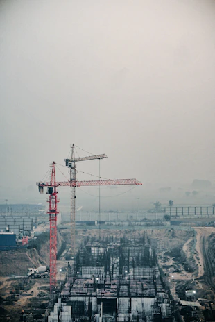 Construction team coordinating on site with cranes and concrete structures in the background.