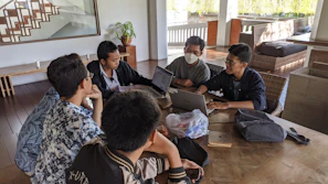 Group of five people discussing AI tools around a table in a cozy room