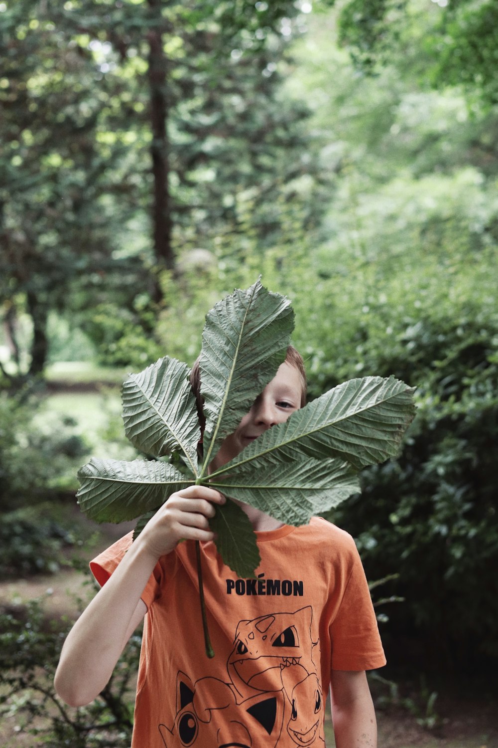 a person holding a large leaf over their face