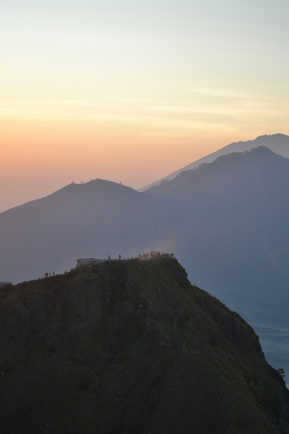 the sun is setting over a mountain with a house on it