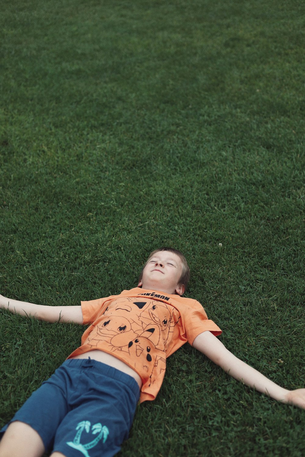 a young boy laying on the grass with a frisbee