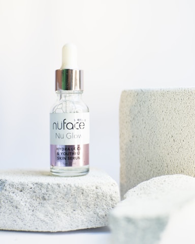 Close-up of the correcting glow serum bottle resting on ivory silk fabric.