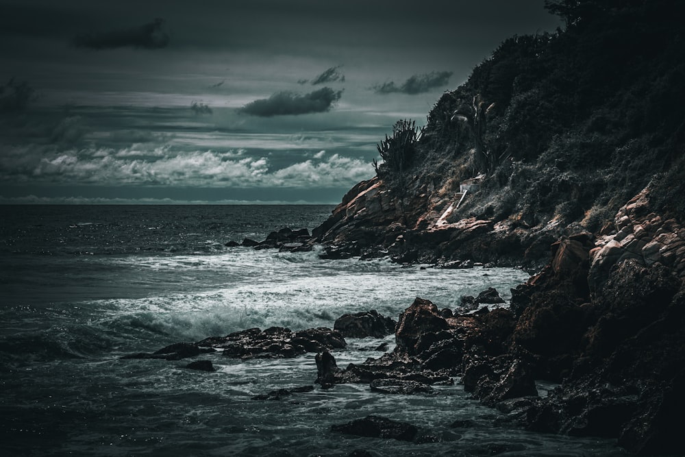 a black and white photo of the ocean and rocks