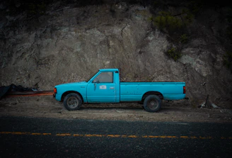 a blue pick up truck parked in front of a mountain