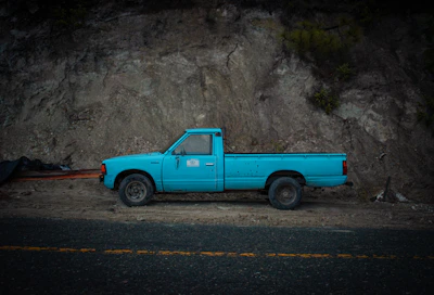 a blue pick up truck parked in front of a mountain