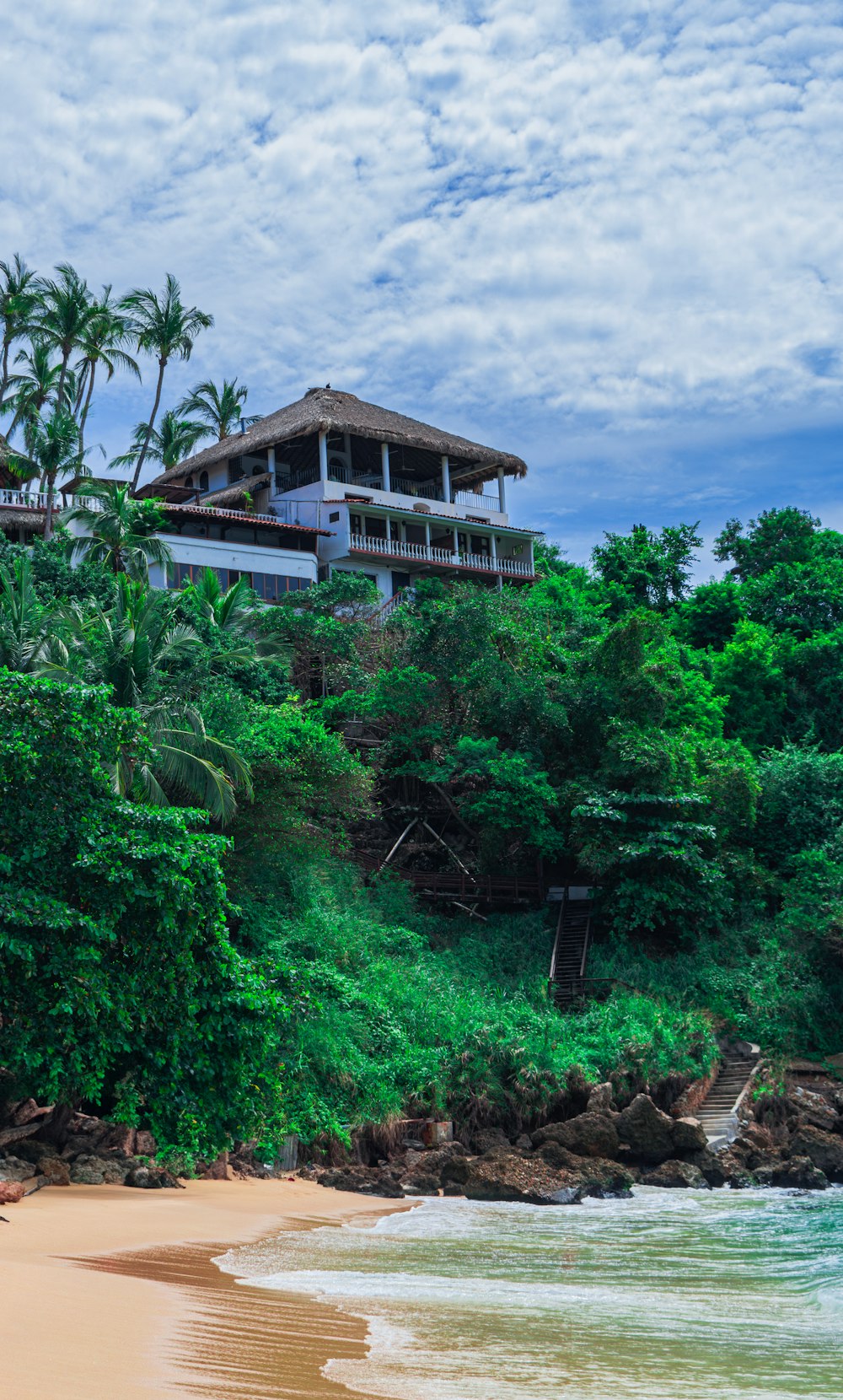 a beach with a house on top of a hill