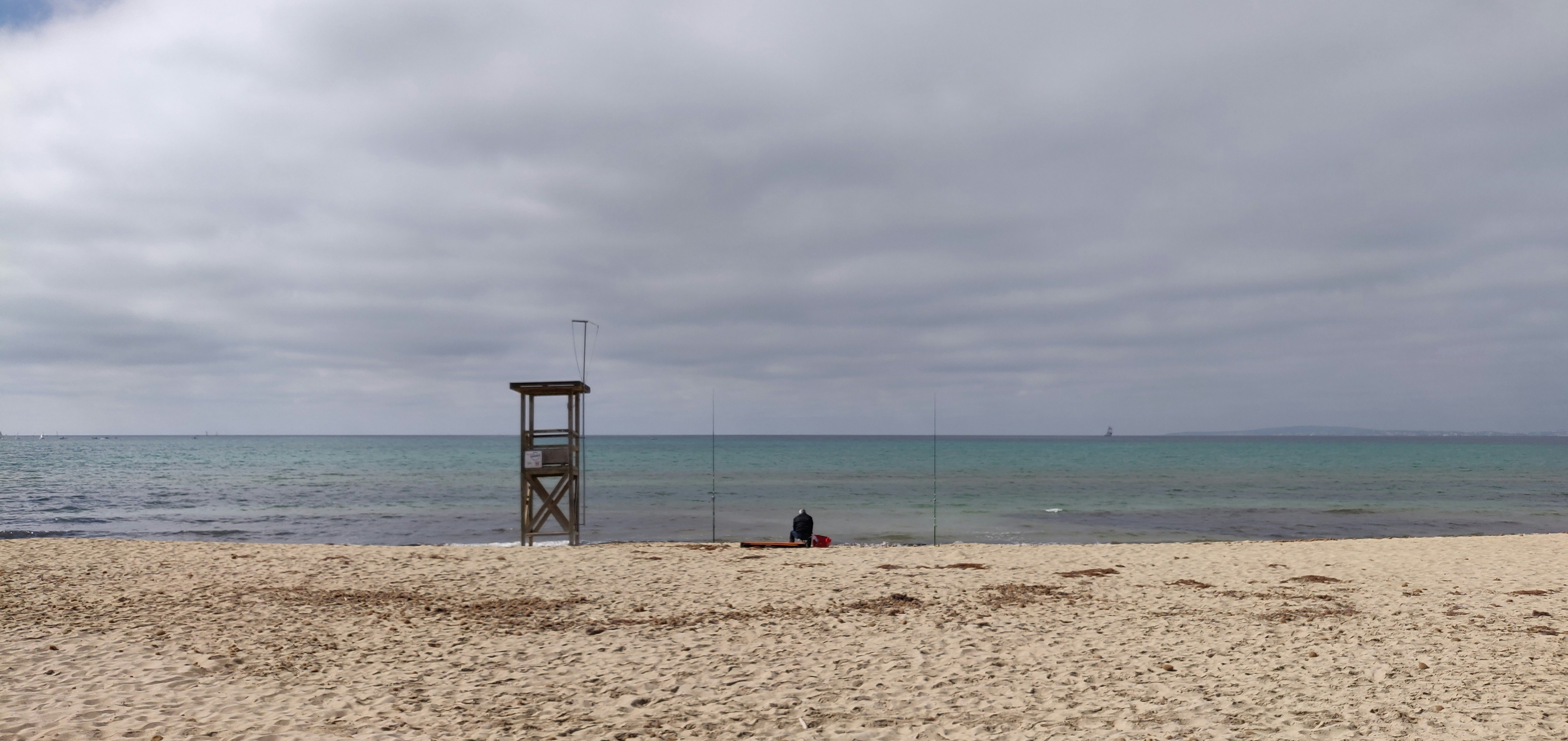 a person sitting on a beach next to the ocean, 