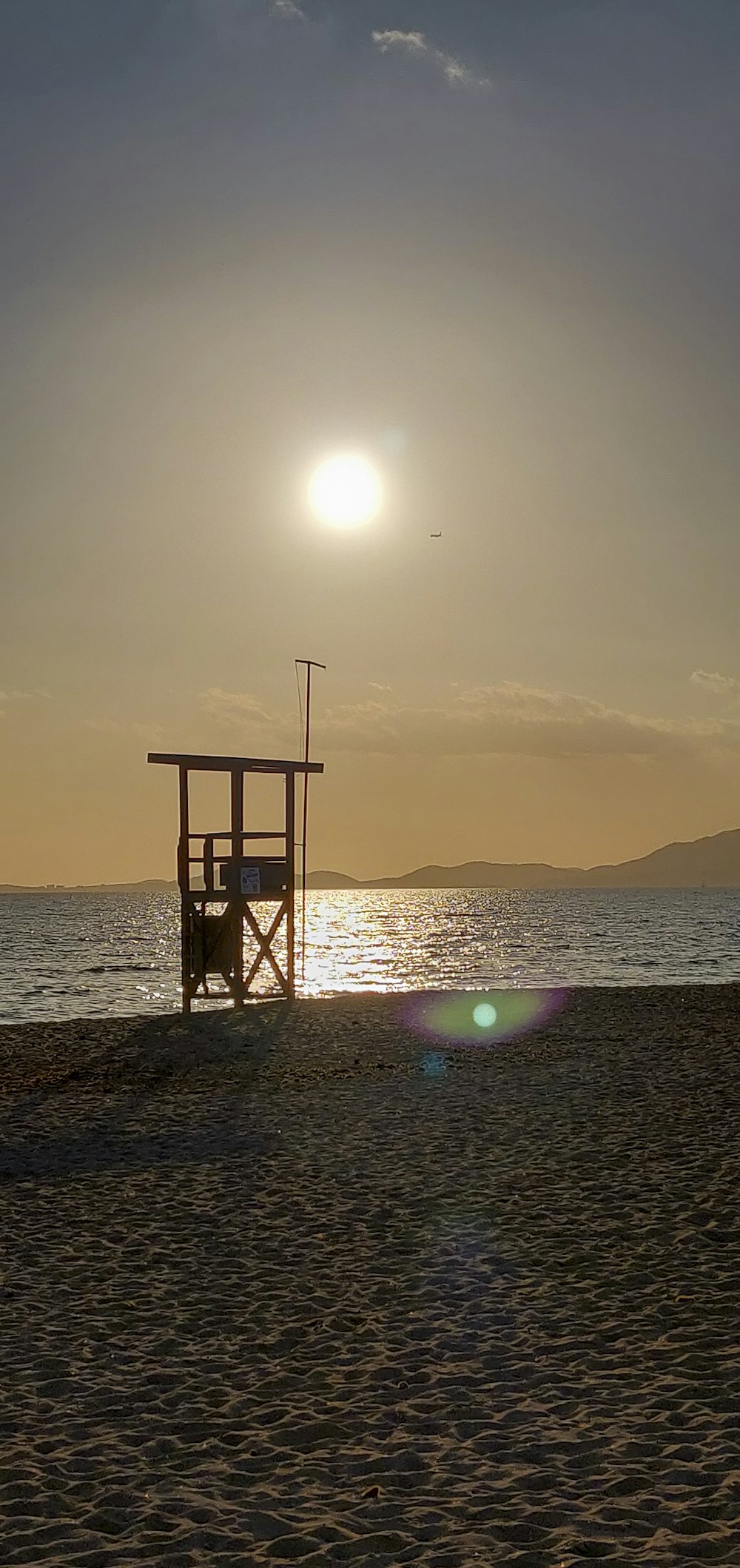 a lifeguard stand on the beach at sunset