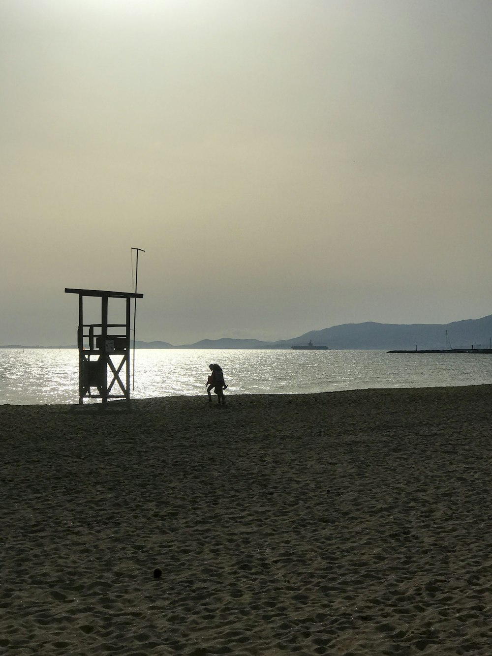 a person sitting on a beach next to a life guard tower