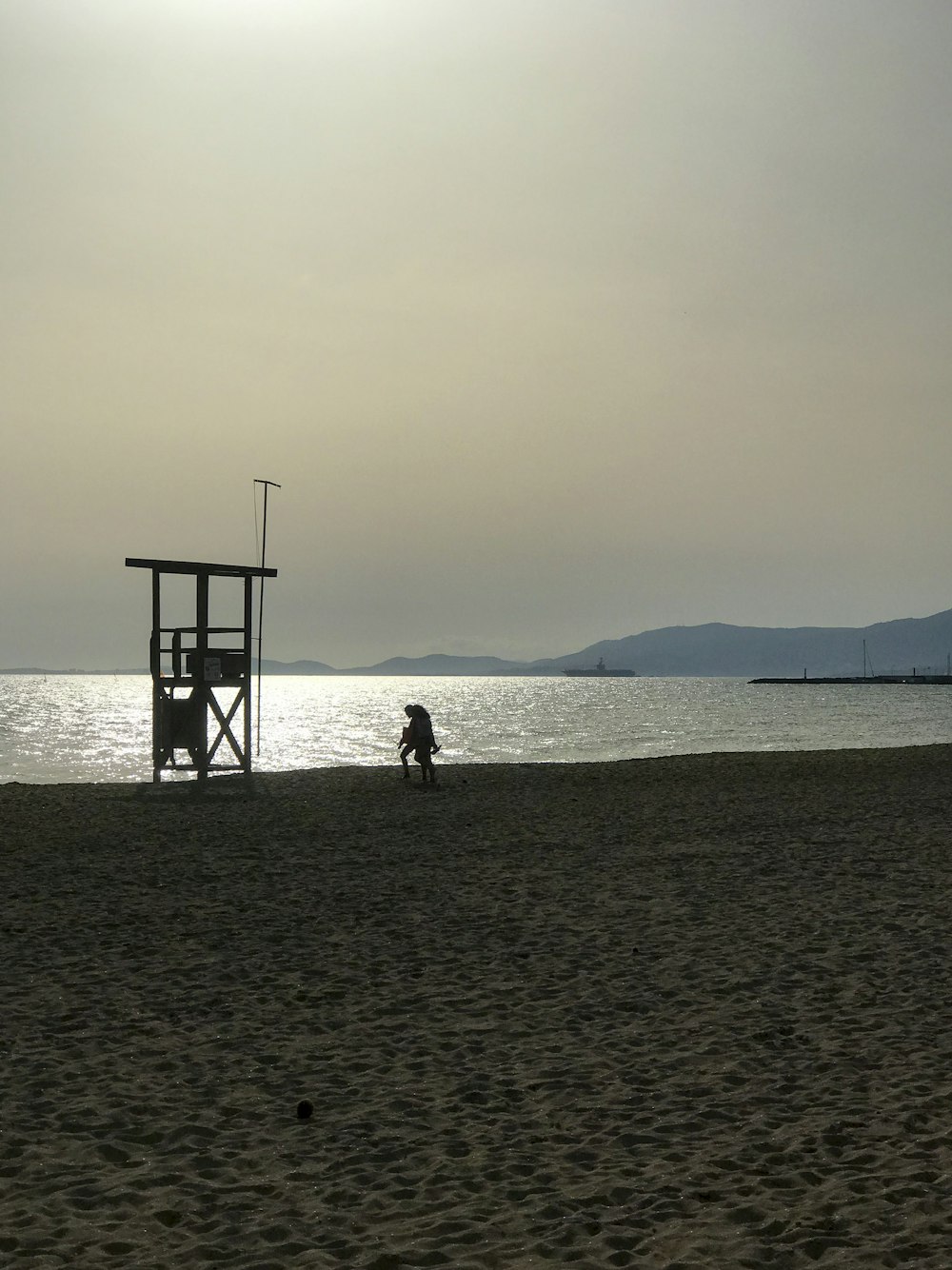 une personne assise sur une plage à côté d’une tour de sauvetage