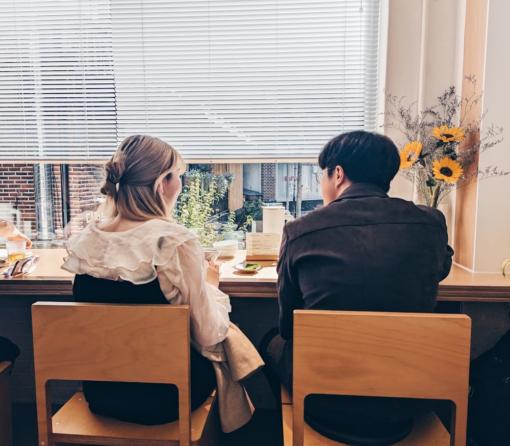 a man and a woman sitting at a table in front of a window