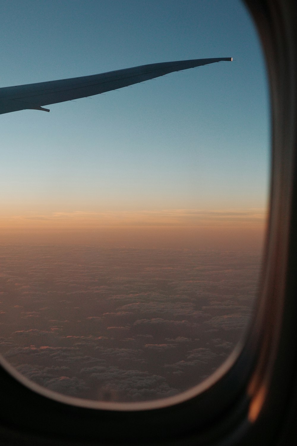 a view of the wing of an airplane as it flies over the clouds