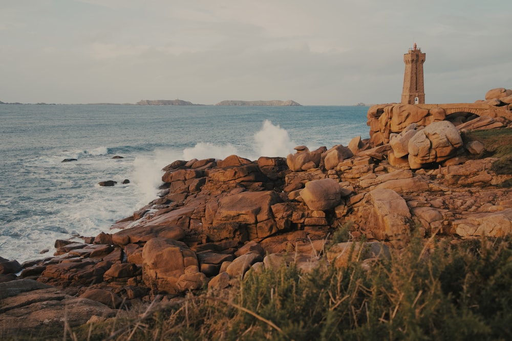 a lighthouse sitting on top of a rocky cliff next to the ocean