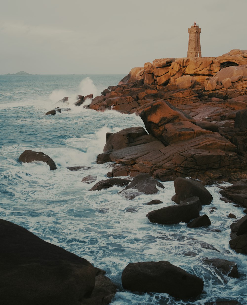 a lighthouse on top of a rocky cliff next to the ocean