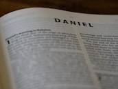 Close-up of an open book authored by d. a. daniel resting on a wooden desk.