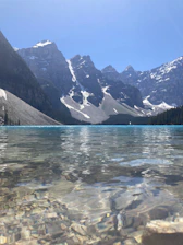 A crisp alpine lake with turquoise water reflecting snow-capped peaks under a clear sky.