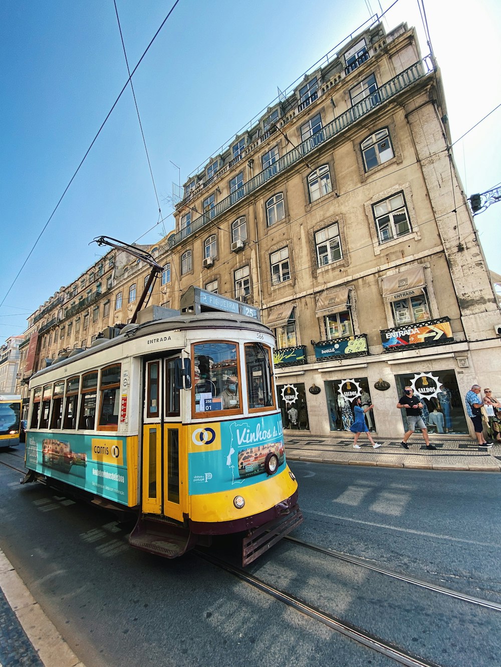 a yellow and blue trolley car traveling down a street