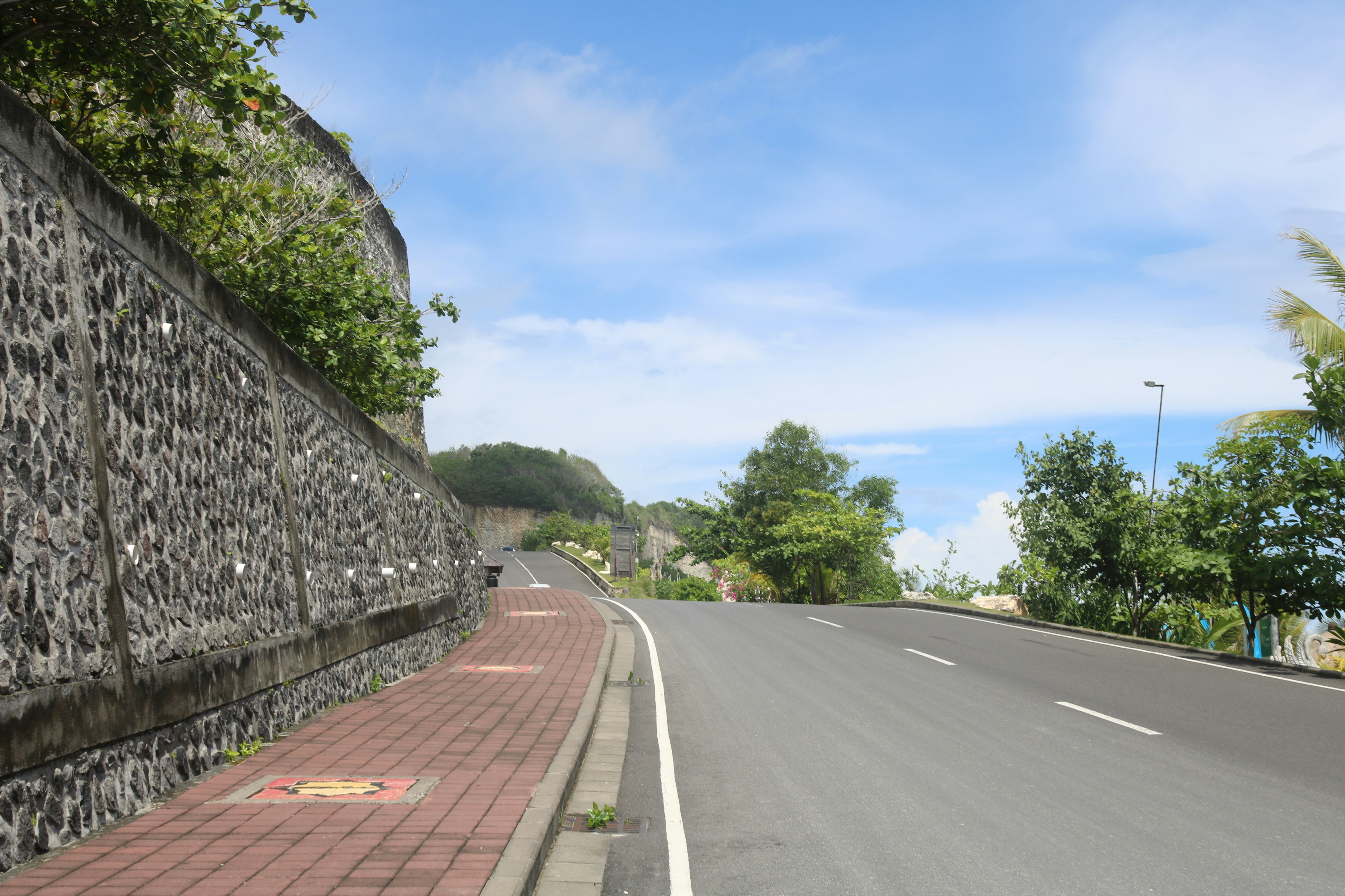 a paved road with a stone wall on the side