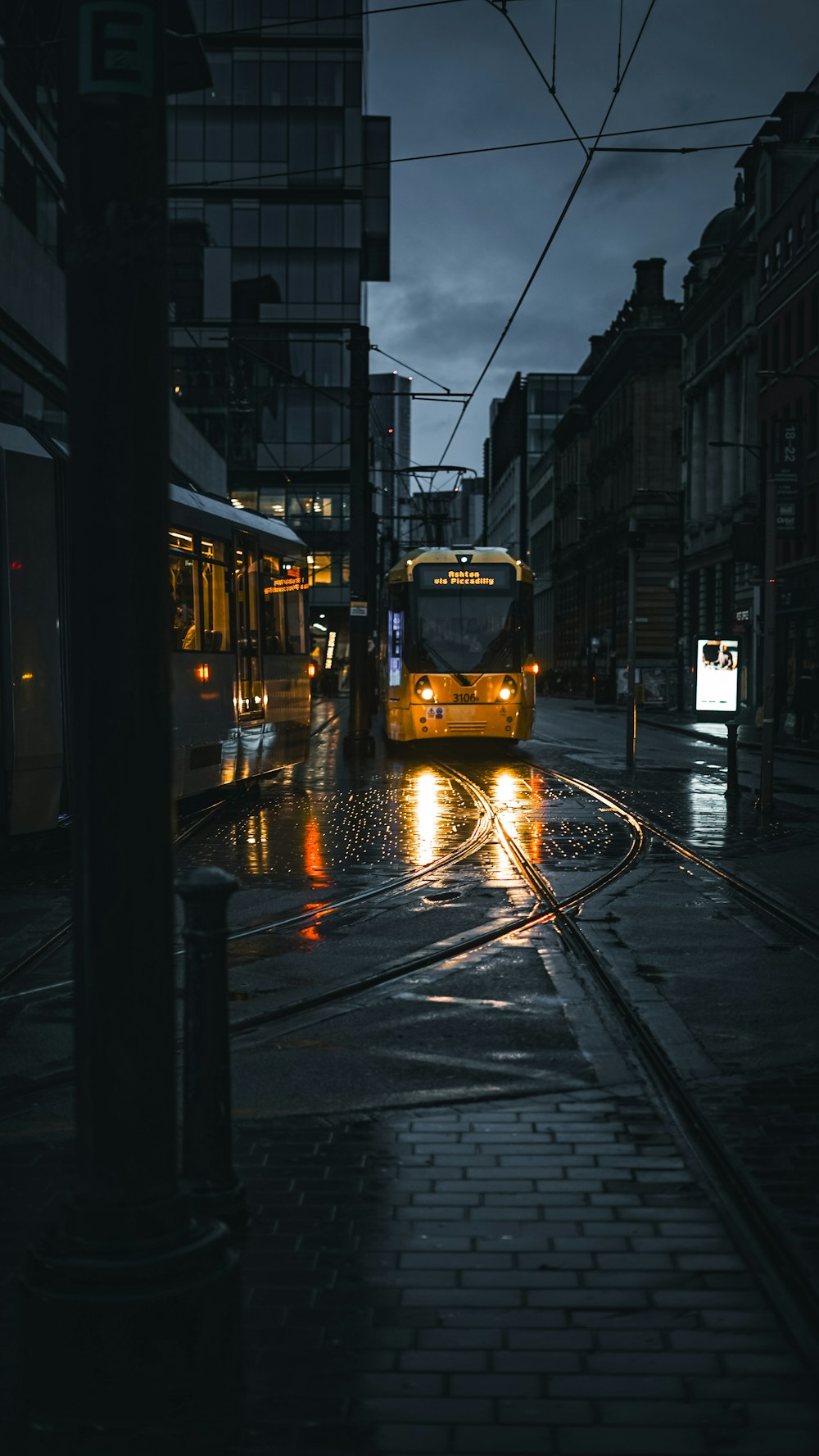 a yellow bus driving down a rain soaked street