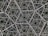 An intricate geometric pattern composed of interlocking hexagonal shapes, creating a sense of infinite depth. The design appears metallic with a dark background, giving the illusion of a three-dimensional structure.