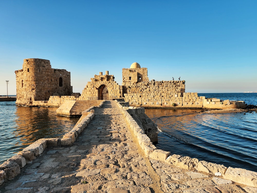 a stone walkway leading to a castle on the water