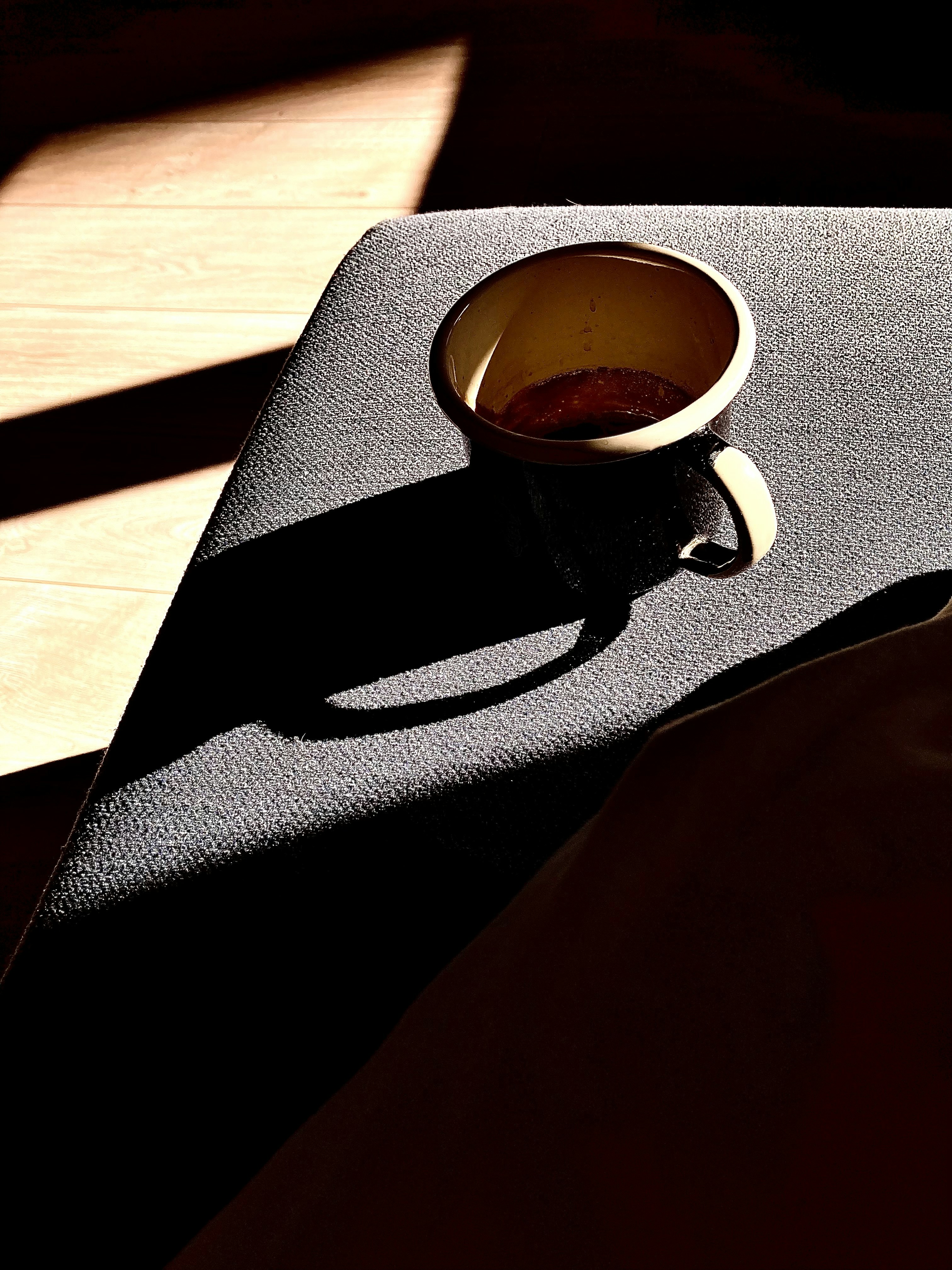 Espresso coffee in glass on dark stone surface, moody atmospheric shadows, deep contrast lighting