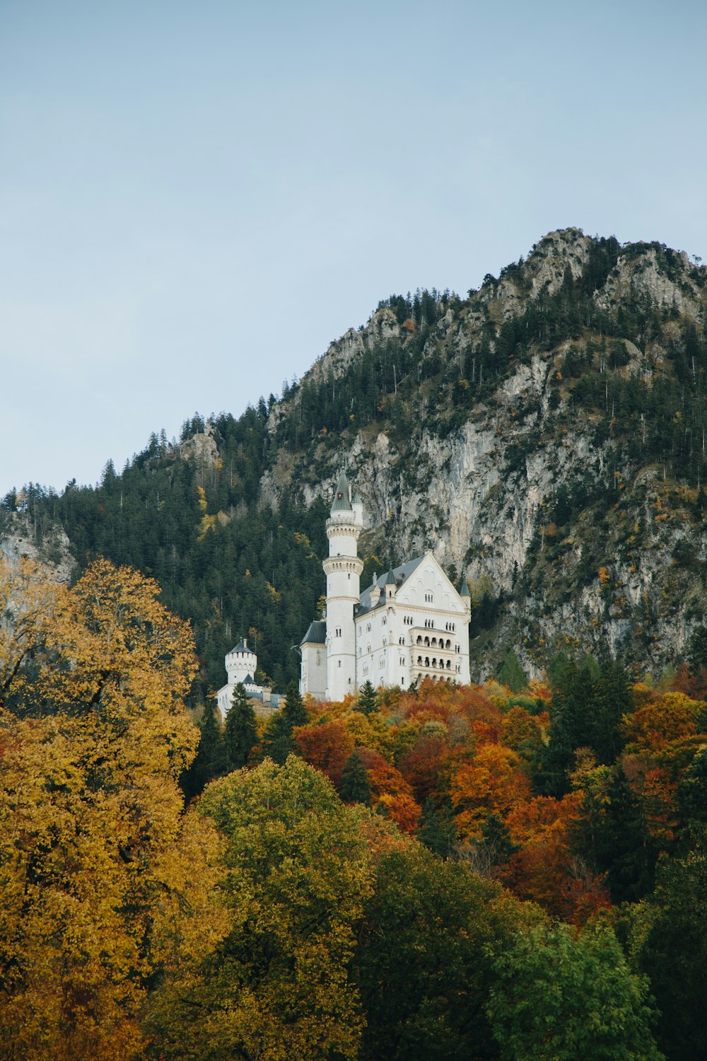 a large white building sitting on top of a lush green hillside