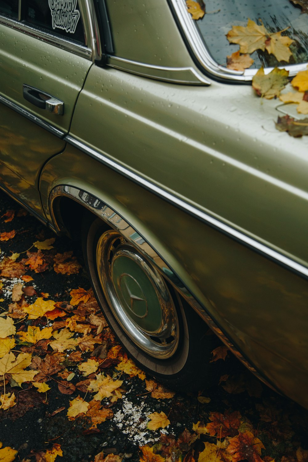 a green car parked on top of a pile of leaves