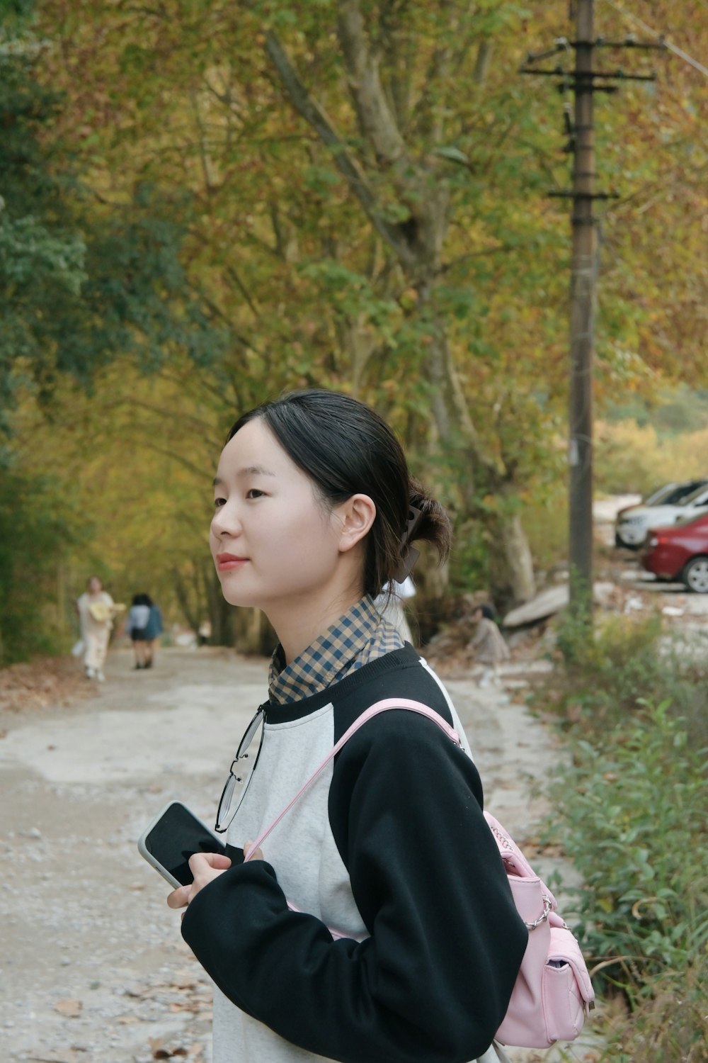 a woman standing on a road holding a cell phone