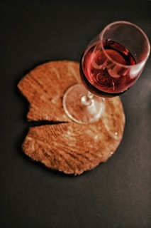 A lively glass of red wine with a playful splash on a rustic wooden table, surrounded by casual wine accessories.