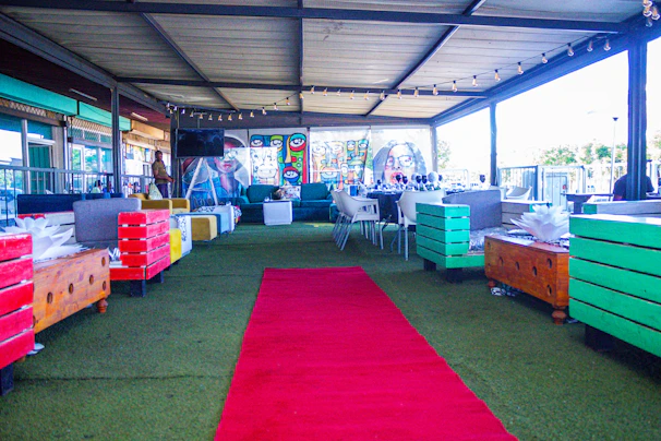 Outdoor plaza furnished with wooden benches and tables, surrounded by vibrant murals.