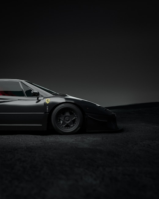 A sleek, black sports car with a low profile, displaying a logo on its side and detailed wheels. The setting is a dimly lit environment with a soft gradient background.