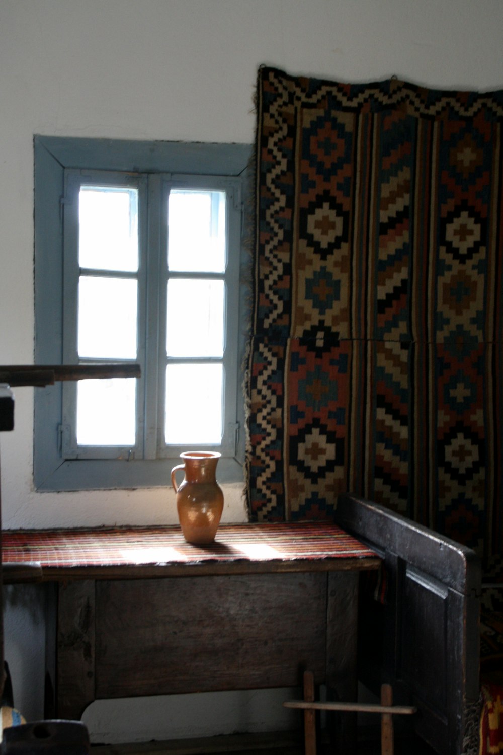 un vaso seduto sopra un tavolo di legno accanto a una finestra