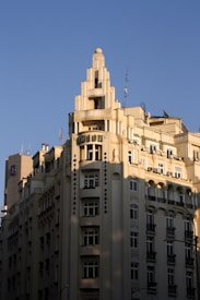 A tall, cream-colored Art Deco building with multiple stories and a decorative top rises against a clear blue sky. The architecture features vertical lines and ornate details, with many windows and a prominent sign reading 'UNION' near the top.