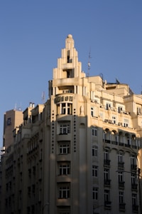 A tall, cream-colored Art Deco building with multiple stories and a decorative top rises against a clear blue sky. The architecture features vertical lines and ornate details, with many windows and a prominent sign reading 'UNION' near the top.