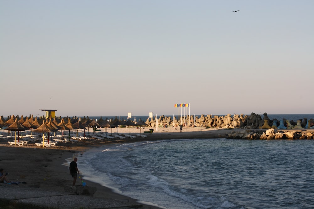 a group of people standing on top of a beach next to the ocean