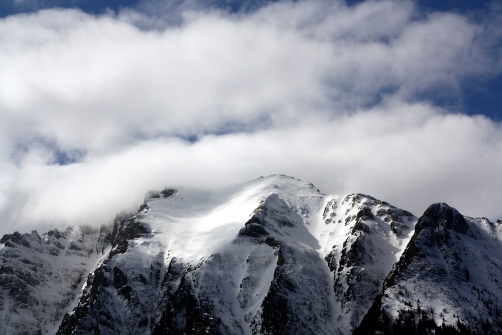 a mountain covered in snow under a cloudy sky