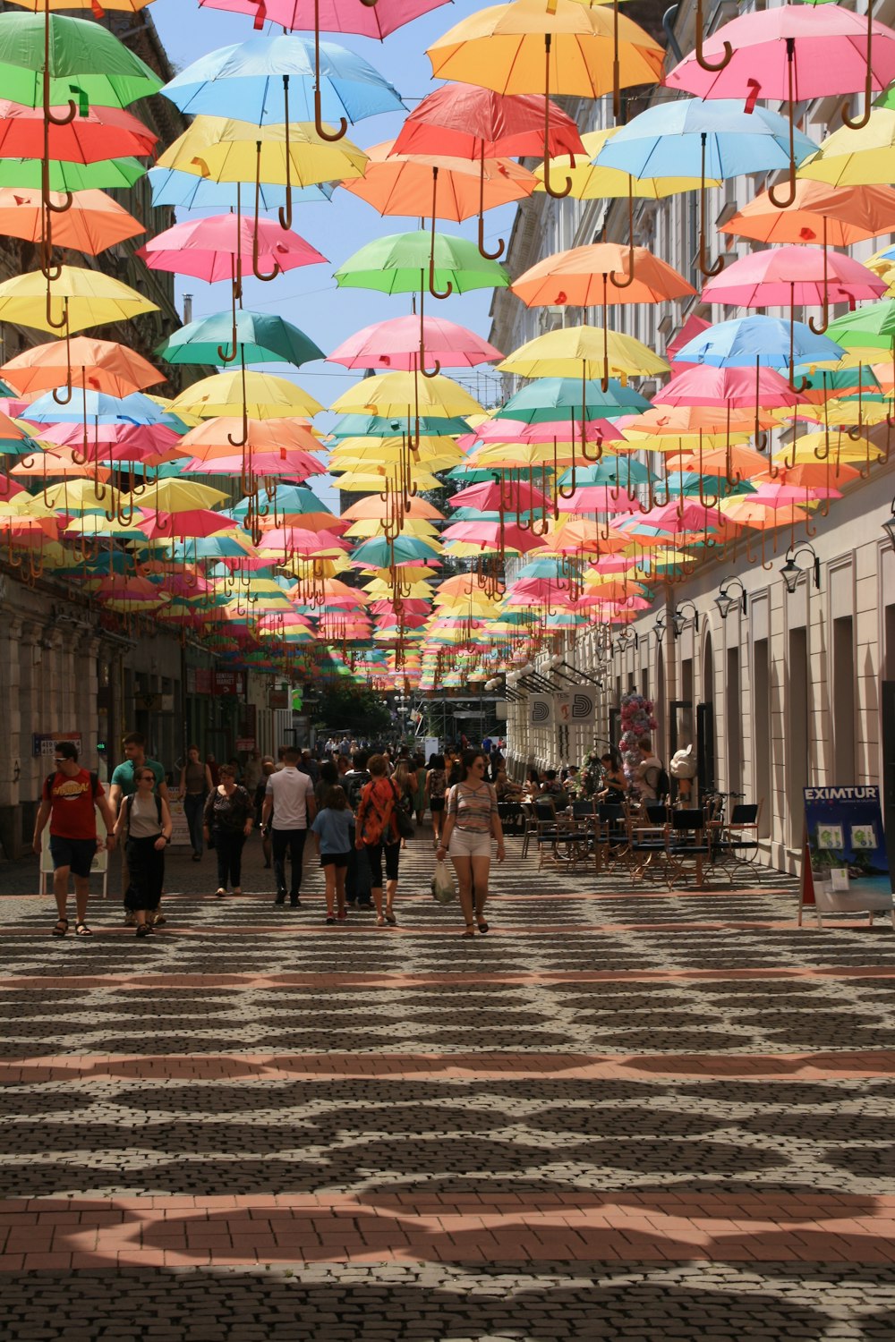 a group of people walking down a street under colorful umbrellas