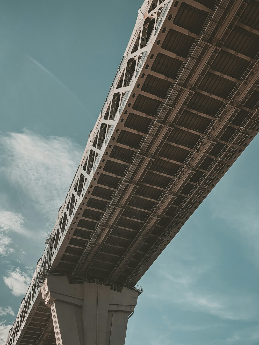 the underside of a bridge against a blue sky