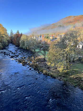 A peaceful river winding through a Yorkshire valley, framed by autumn foliage.