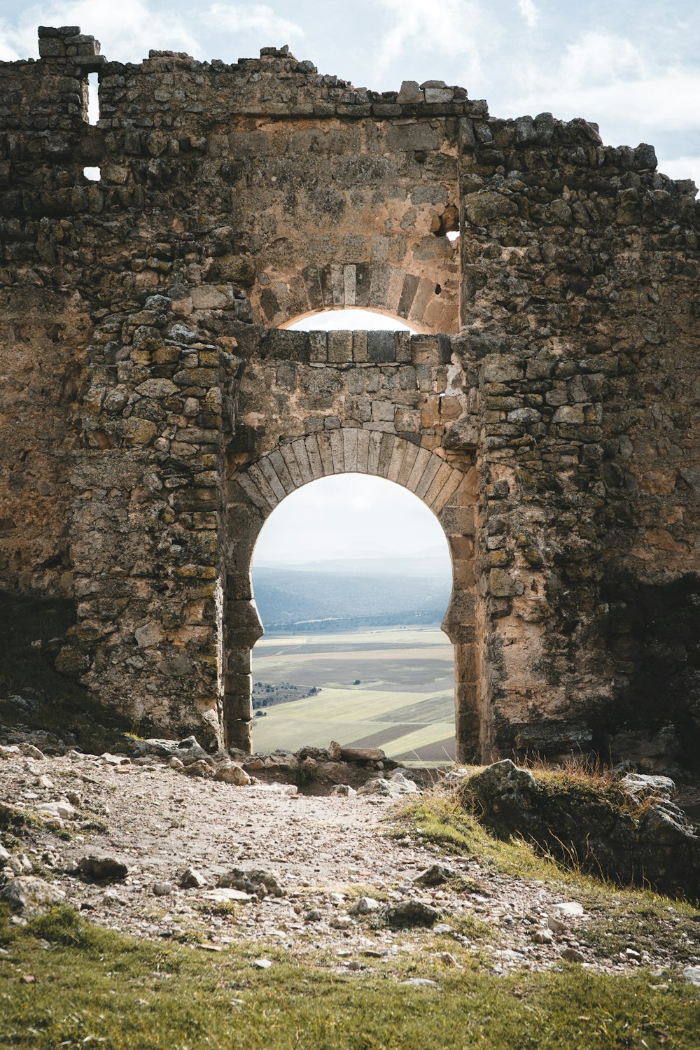 a stone arch with a view of a valley