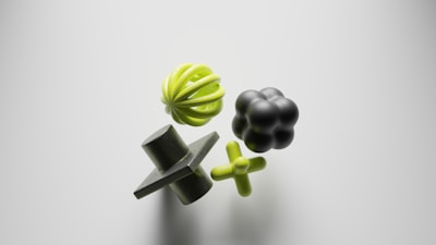 Four abstract geometric shapes float against a light background. The objects include a green sphere with curved ridges, a black rounded shape resembling a cluster of spheres, a green plus-shaped figure, and a dark green cone with a square intersecting its middle.