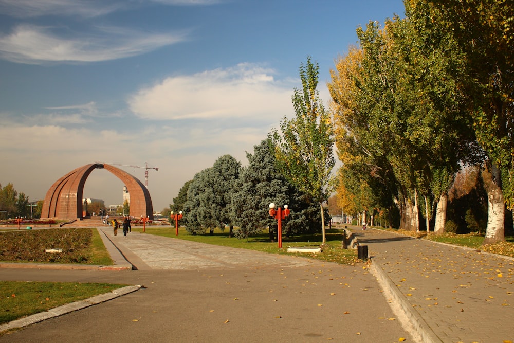 a person walking down a road near a large arch