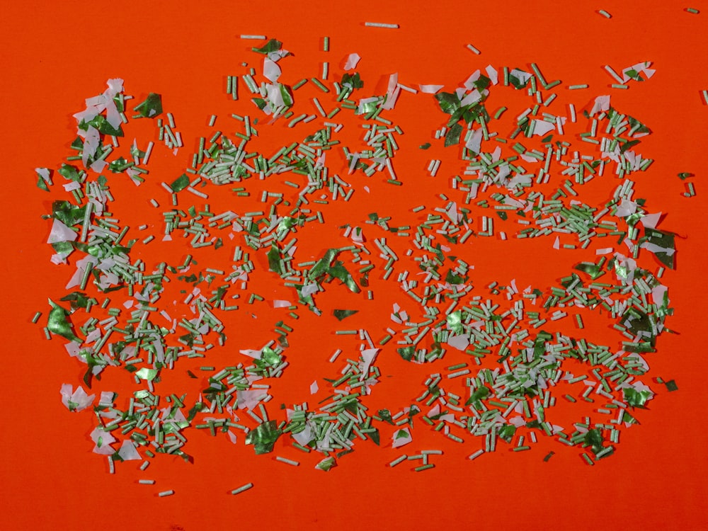 a pile of shredded green paper on a red surface