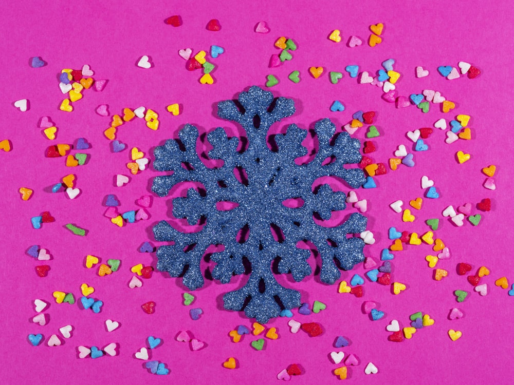 a blue snowflake surrounded by hearts on a pink background
