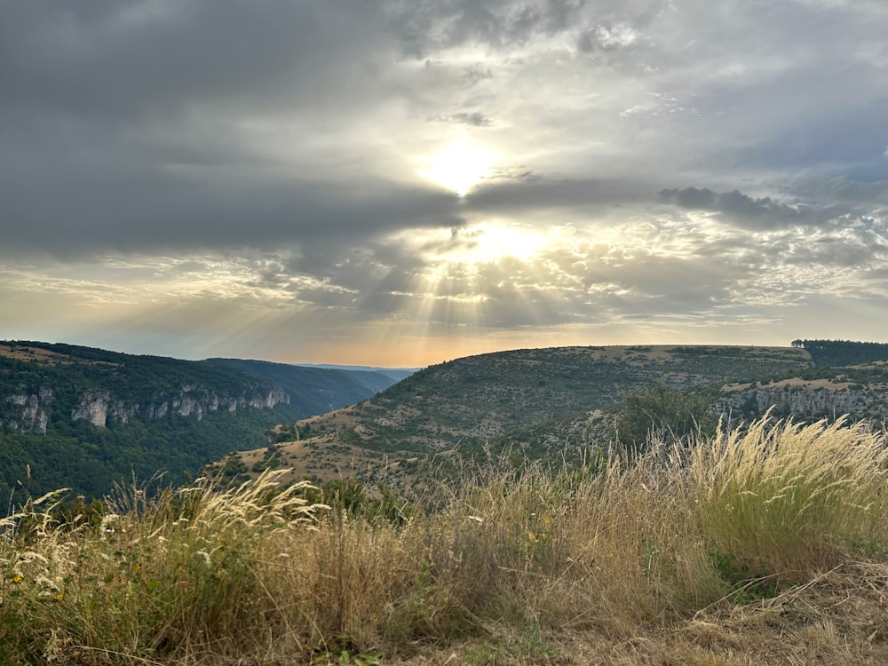 O sol brilha através das nuvens sobre as montanhas