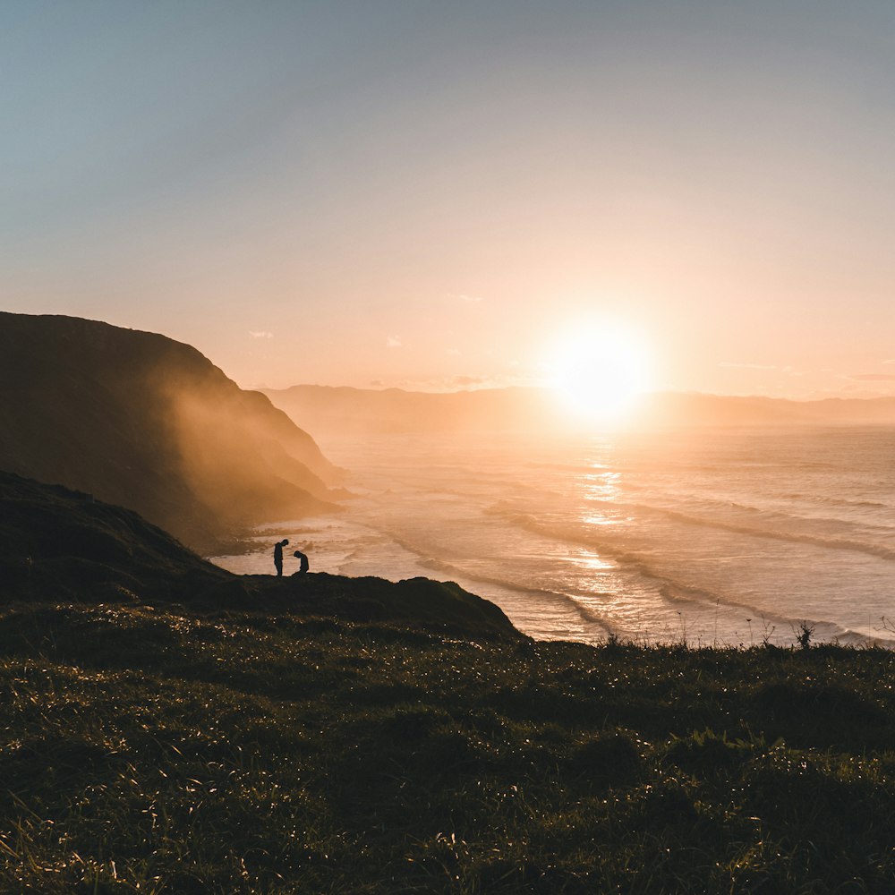 a couple of people standing on top of a lush green hillside